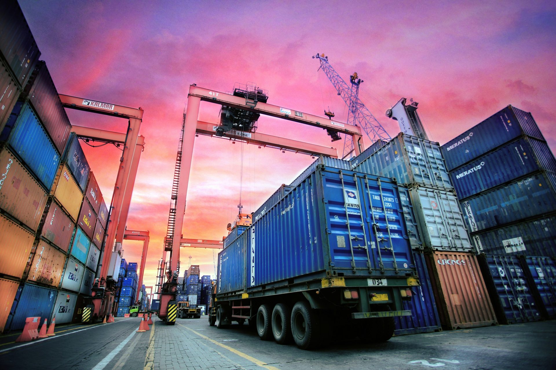 Bei Sonnenuntergang in einem geschäftigen Hafen gestapelte Schiffscontainer.